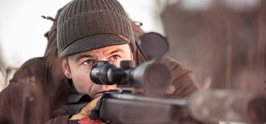 Fjallraven hunting gear in action, featuring a hunter aiming through a rifle scope. High-performance outdoor apparel designed for serious hunters in rugged environments.