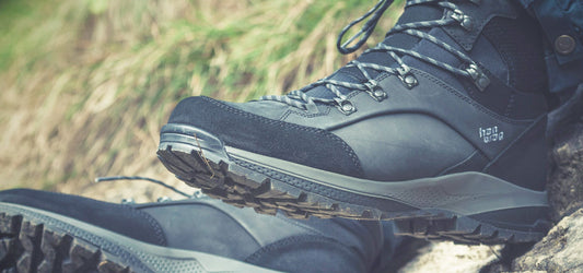 Close-up of a pair of Hanwag hiking boots resting on rocky ground, highlighting the rugged tread and durable design.