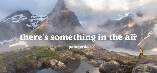 Patagonia outdoor clothing, featuring a hiker in a yellow jacket exploring a mountainous landscape with mist and dramatic peaks. Perfect gear for adventurous and rugged terrains.